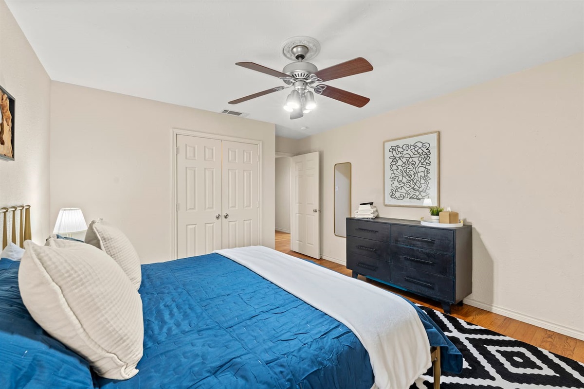 Recharge in this cozy bedroom featuring a plush king bed, stylish dresser, and sleek ceiling fan — the perfect blend of comfort and function.