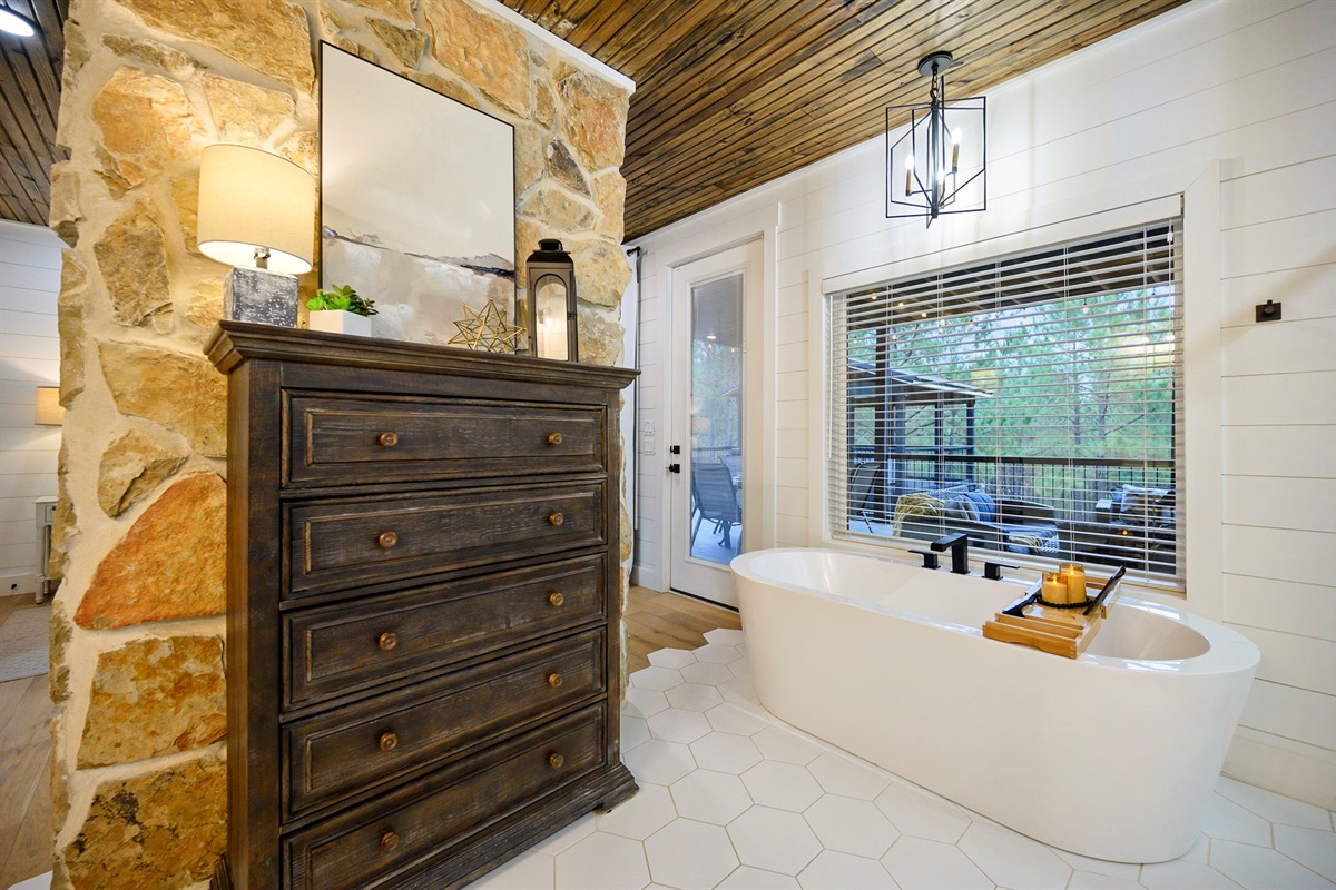 Freestanding soaking tub with forest views for total relaxation.