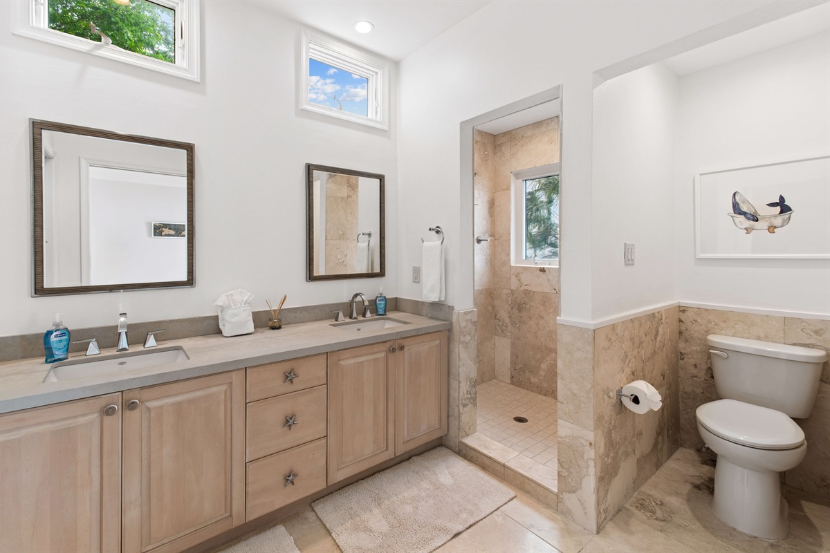 Modern bathroom with double vanity, hair dryer, walk-in shower, and spa-like vibes to refresh after a beach day.