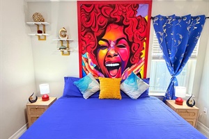 Closer look at the queen bedroom, highlighting the comfy bed, bold artwork above, and bedside lamps on each side.edroom, highlighting the comfy bed, bold artwork above, and bedside lamps on each side.