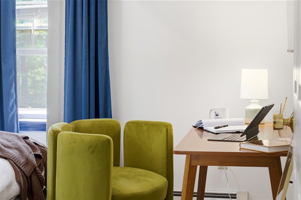 A cozy bedroom featuring a dedicated workspace, thoughtfully designed for comfort and productivity in a peaceful setting.
