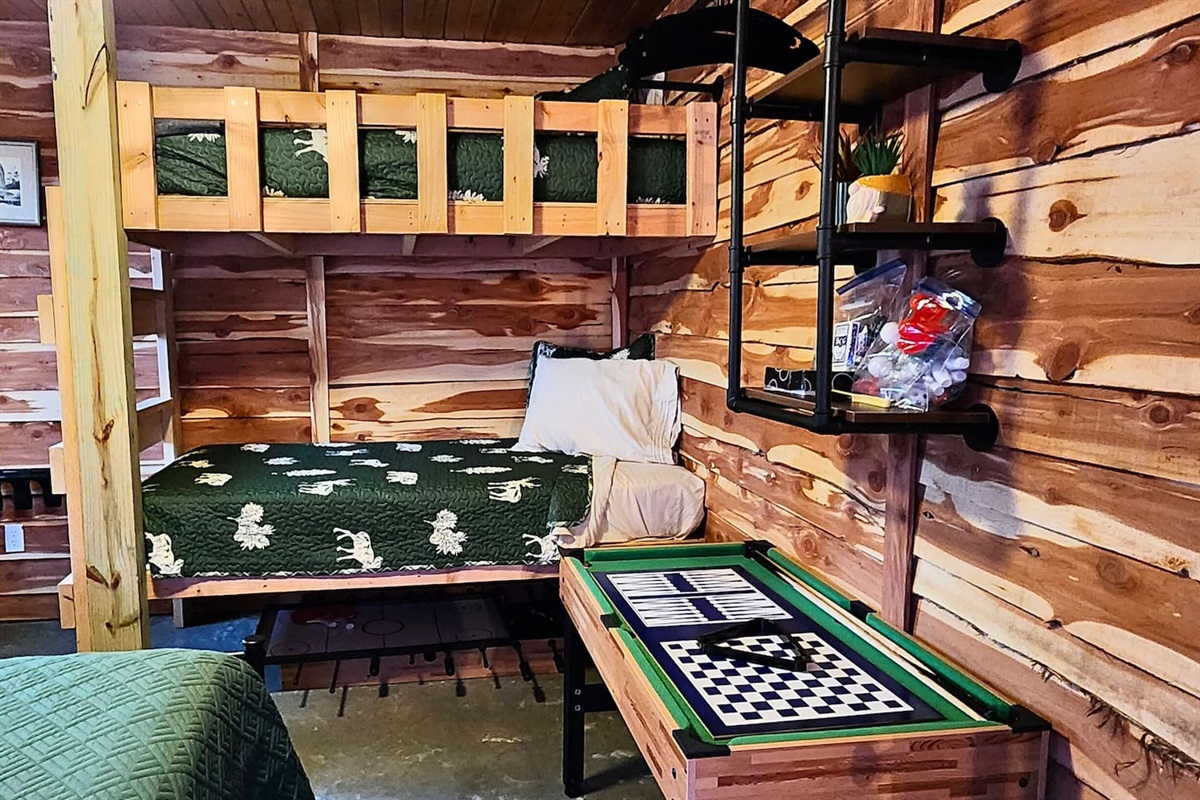 A cozy bunk room with rustic twin beds, woodsy bedding, and fun for all ages. Enjoy the multi-game table and shelves stocked with games and activities—perfect for kids or friends to unwind after a day of outdoor adventure.
