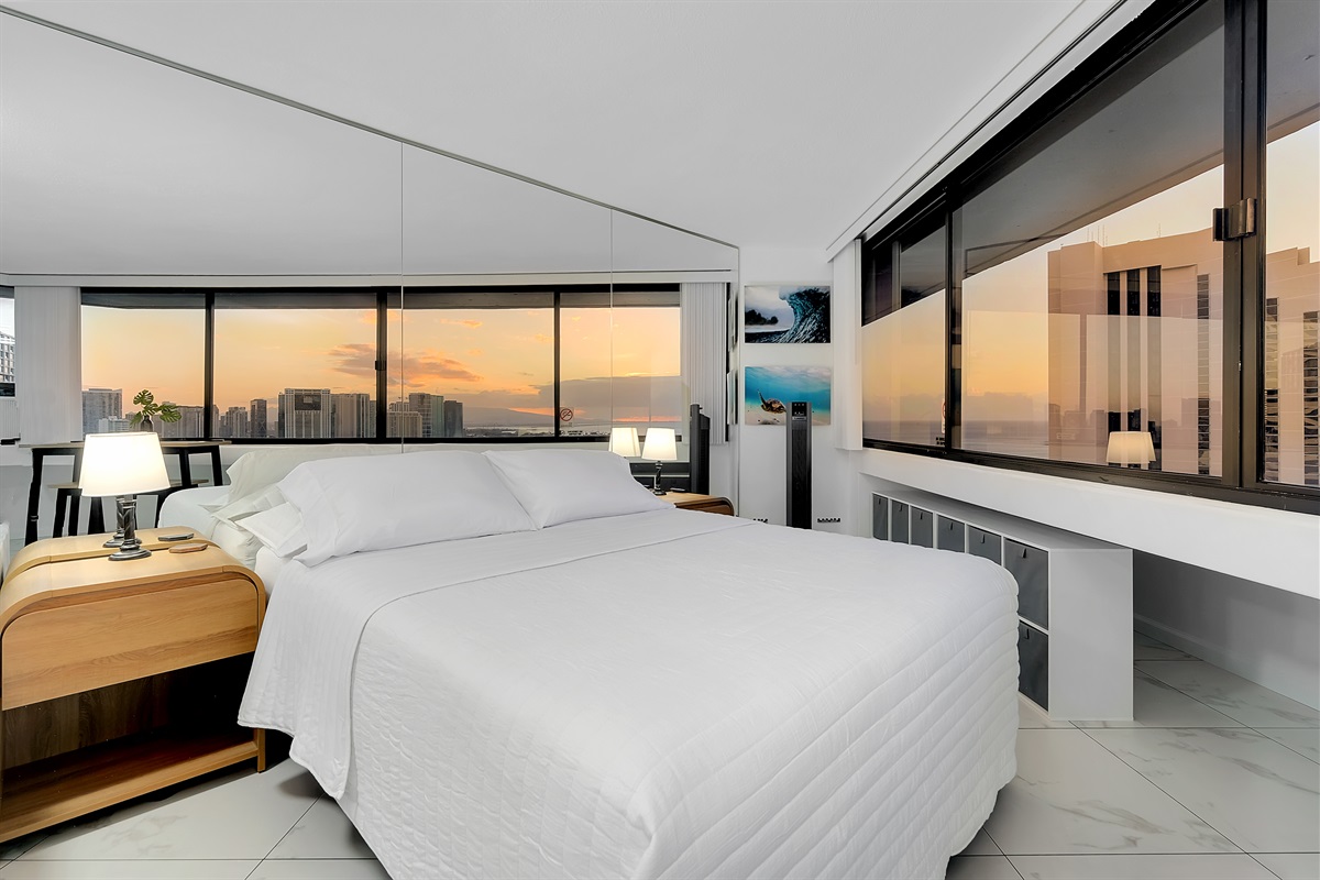 Drift into relaxation with panoramic ocean and skyline views from your plush Waikīkī retreat. Surrounded by floor-to-ceiling windows, this serene bedroom invites you to unwind as the island sunsets paint the horizon in shades of gold.