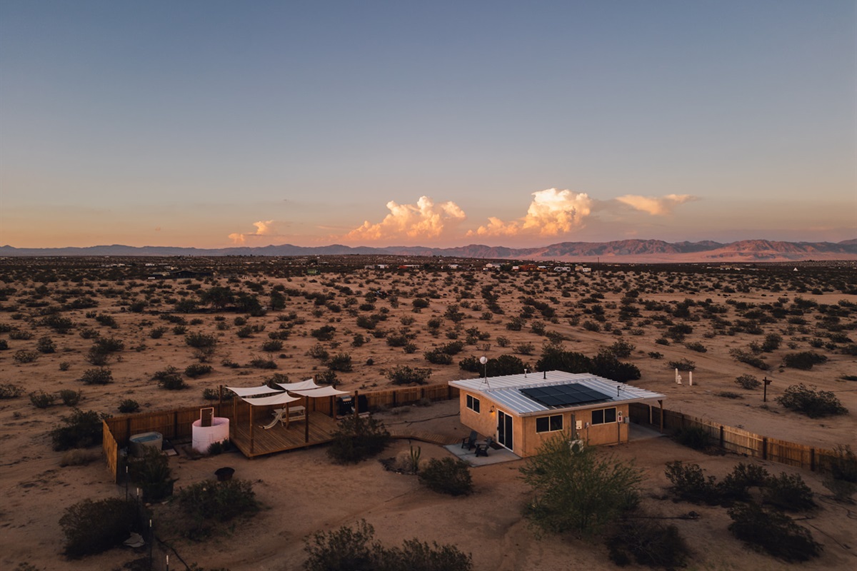 Aerial view of Pink Moon cabin nestled on 2.5 acres of private desert land with panoramic mountain and Joshua Tree vistas.
