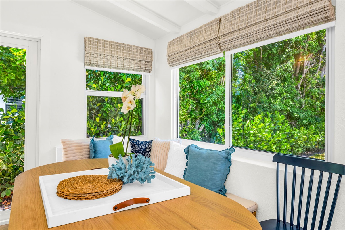 Sun-drenched sophistication—this inviting Florida room features seating for six, a chic bar cart, and panoramic pool views framed by bamboo woven shades. Perfect for intimate meals, morning coffee, or evening cocktails with a tropical backdrop.