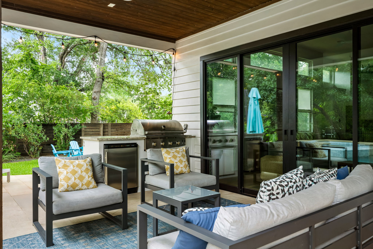 Comfortable outdoor patio lounge with plush cushioned seating, string lights, and easy access to the home's interior — indoor-outdoor living at its finest.