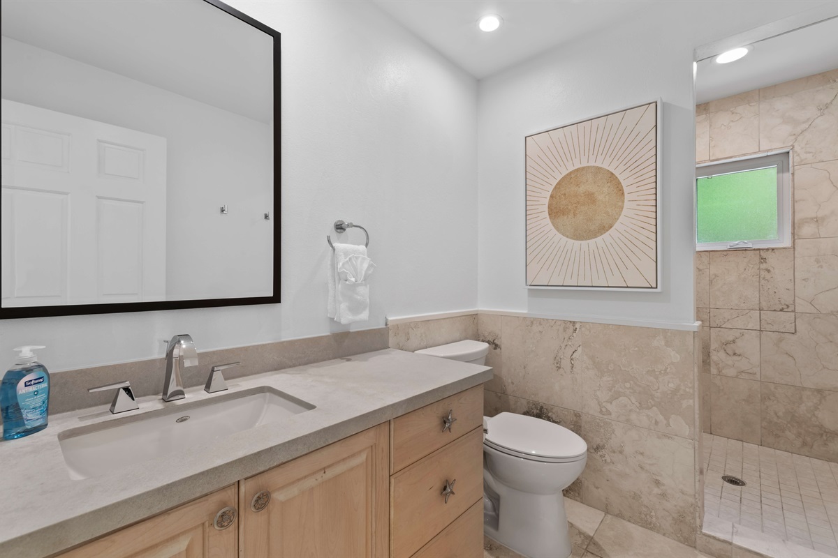 Spacious guest bath with clean finishes, hair dryer, walk in shower, and plenty of counter space.