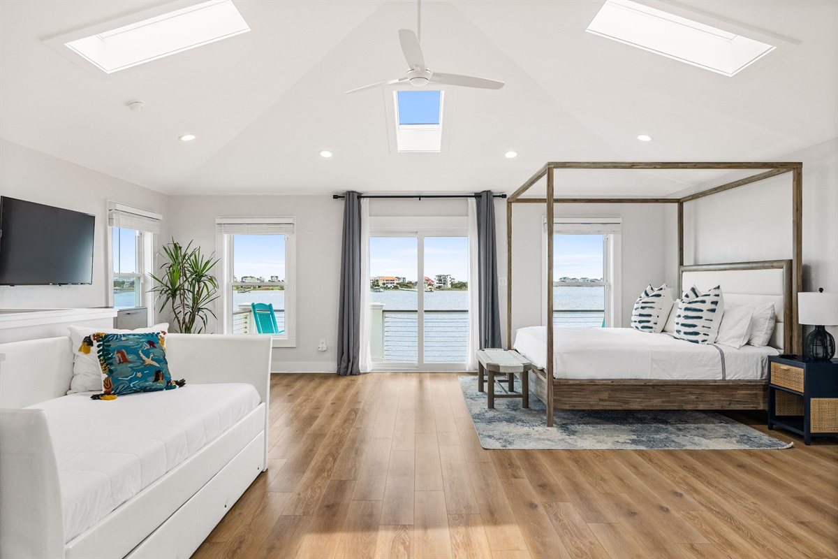 Luxurious top-floor king master suite with private balcony access, stunning water views, and additional twin daybed with trundle for flexible sleeping space