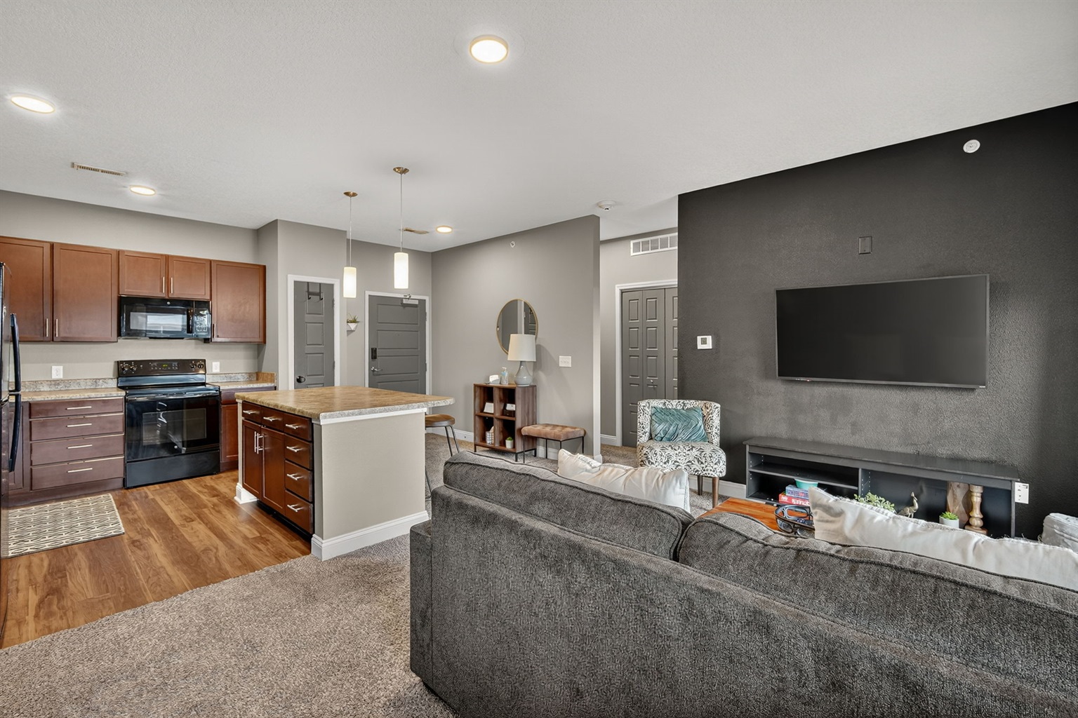 Bright, modern kitchen with full-size appliances and ample counter space. Pendant lights highlight the central island, perfect for coffee, cocktails, or casual meals. Convenient entryway adds