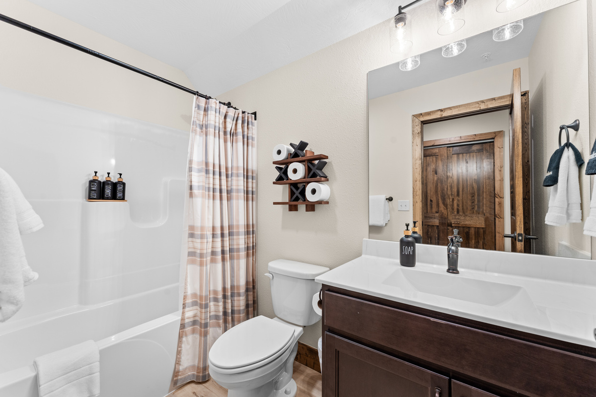 A tub-shower combo with fresh towels and a playful tic-tac-toe nod for the kids.
