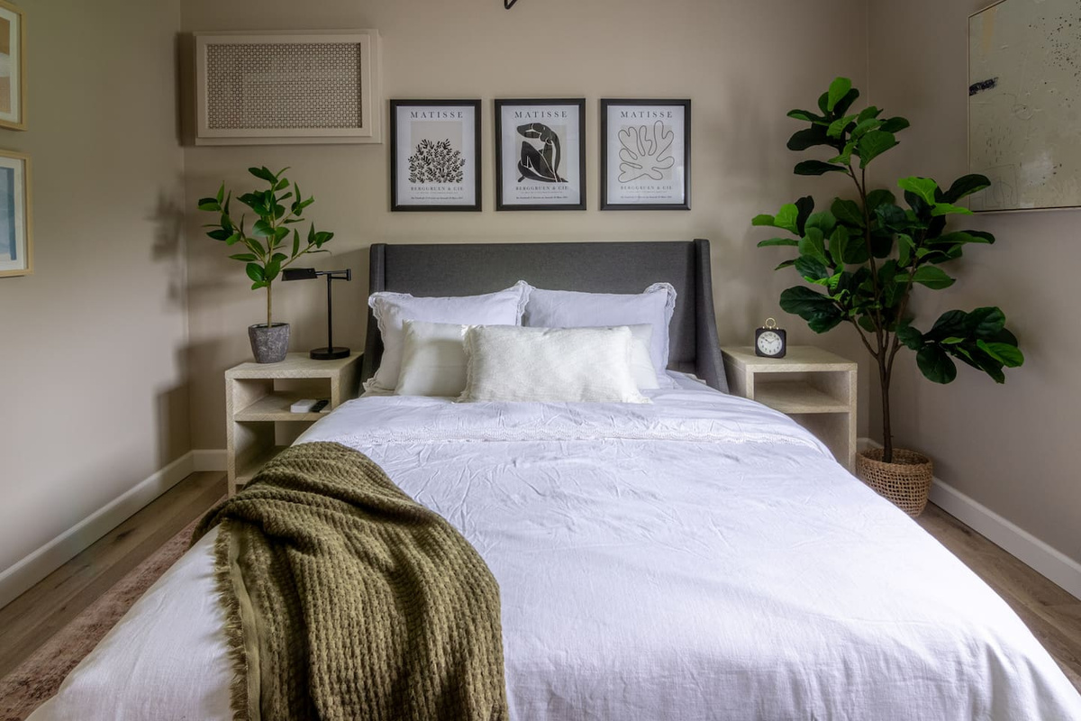 Framed botanical prints and a cozy knit throw give this bedroom a relaxed, layered feel.