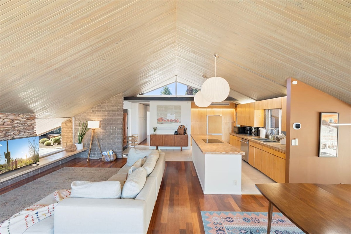 Expansive open living and kitchen area with vaulted wood ceilings, warm finishes, and a seamless flow designed for comfort and gathering.
