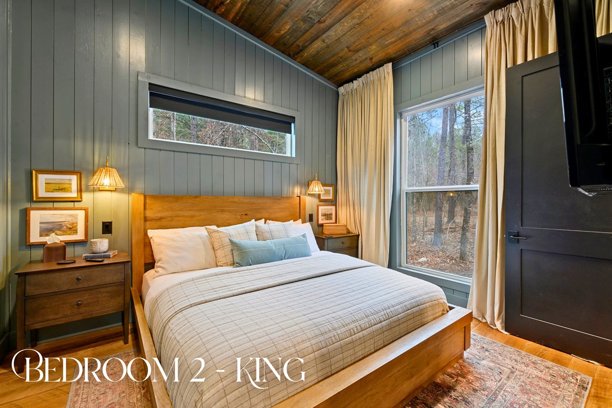 This restful bedroom pairs warm lighting with a comfortable king bed and wide views of the surrounding trees.