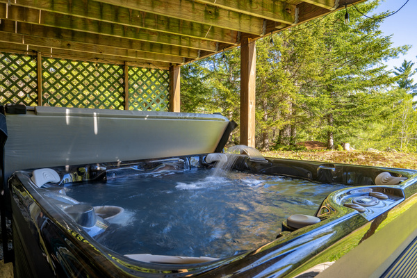 Unwind year-round in the private hot tub, tucked beneath a covered deck and surrounded by peaceful woodland views.