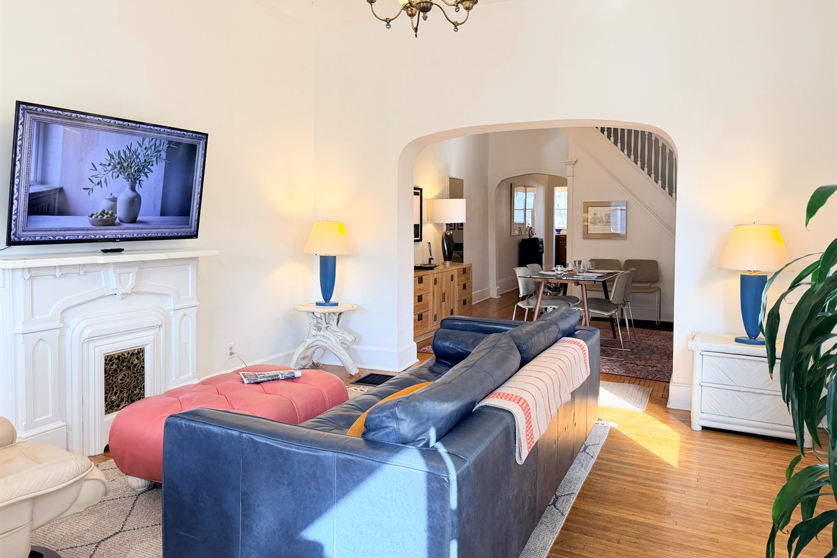 A bright, open view highlighting the room’s scale, natural light, classic arches, and early-1920s charm.