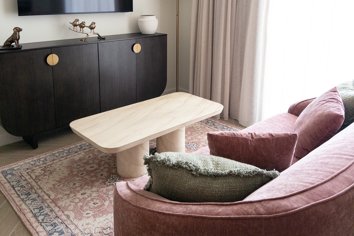 Living area - sculptural sofa, travertine table and a layered vintage rug.