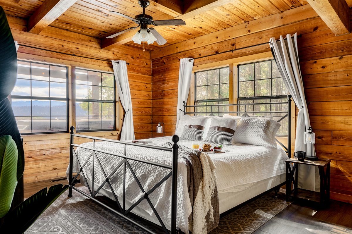 Beautifully designed bedroom featuring elegant wood paneling and a cozy bed. The whole place is covered by beautiful natural views.