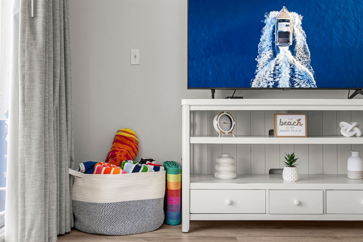 Beach vibes await! Enjoy cozy coastal decor, a smart TV for relaxing nights in, and a basket stocked with colorful beach towels—ready for your next sun-soaked adventure.