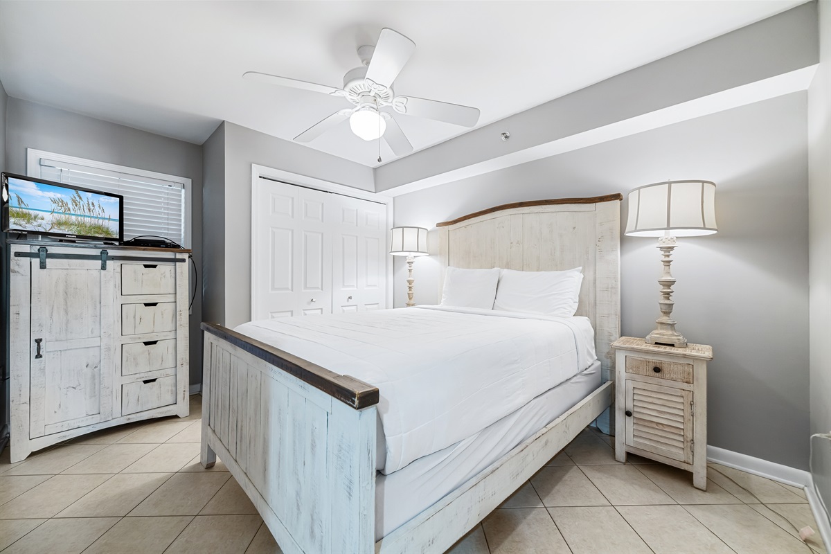 Comfortable king-size bed with crisp white linens, flanked by matching nightstands and lamps,  complemented by practical storage solutions, providing a cozy and inviting space.