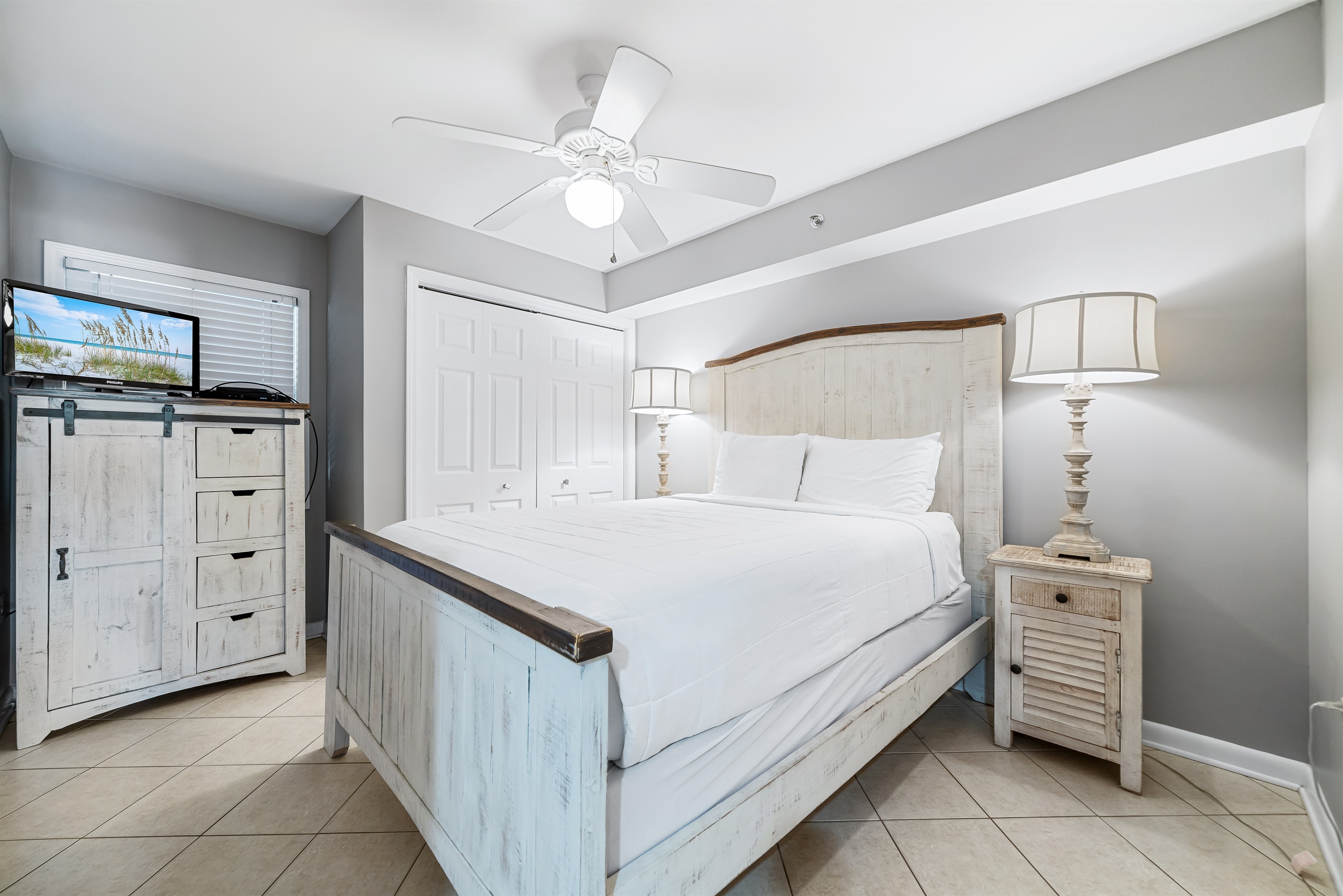 Comfortable king-size bed with crisp white linens, flanked by matching nightstands and lamps,  complemented by practical storage solutions, providing a cozy and inviting space.