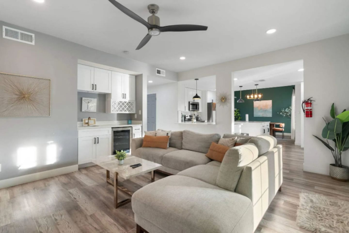 Spacious open-concept living area with modern kitchen, comfortable seating, and forest green accent wall.