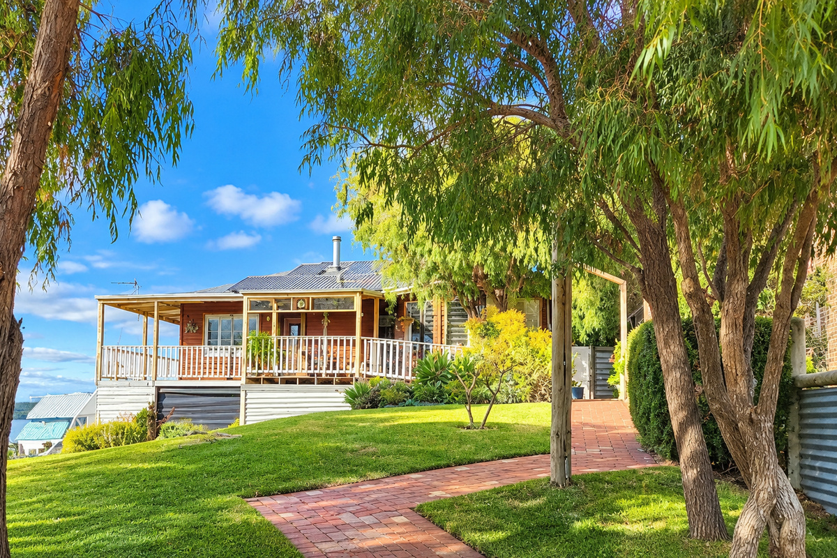 Your coastal escape awaits — a peaceful retreat with charming timber details, green lawns and a welcoming verandah.