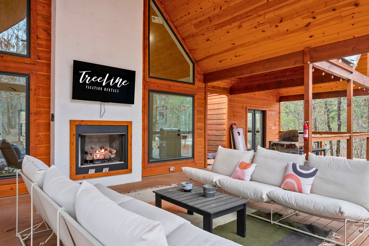 The cozy seating area invites you to settle in by the outdoor fireplace, where comfortable seating and warm wood create the perfect place to gather and unwind.