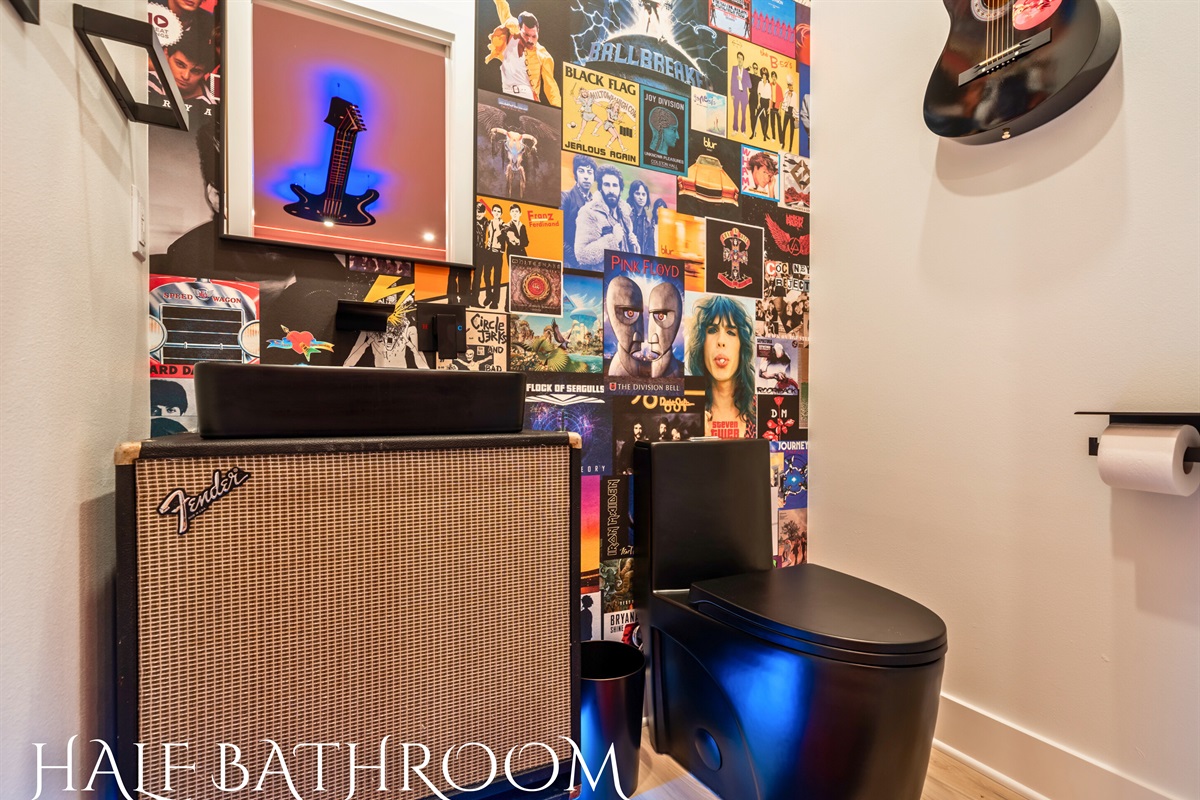 The half bathroom features rock and roll decor, with guitar wall art and album covers creating a nostalgic vibe.