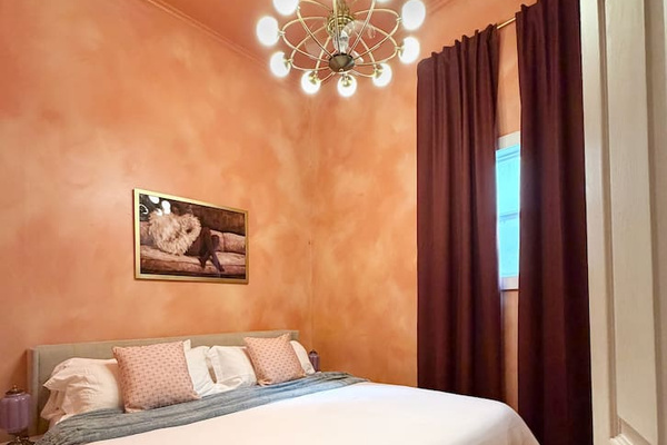 Sink into the plush king bed as the dramatic curtains draw and the ceiling fan hums. Soft light, serious comfort — the peach bedroom is your boutique hotel moment in the heart of NOLA.