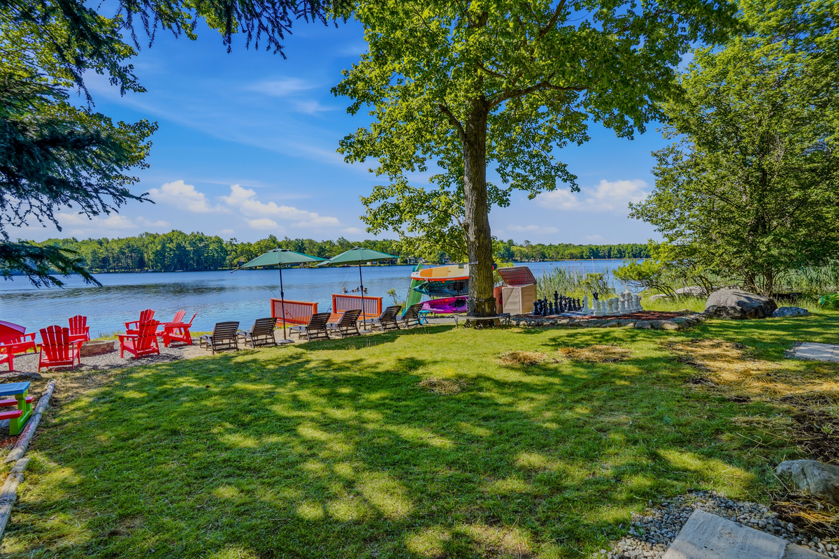 Backyard lawn with red Adirondack chairs and the full sweep of Lake Carobeth