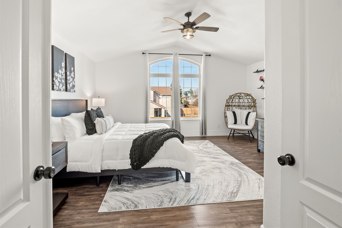 Stunning primary retreat featuring soaring ceilings, statement windows, designer finishes, and a serene sitting nook—luxury and tranquility in one elegant space.