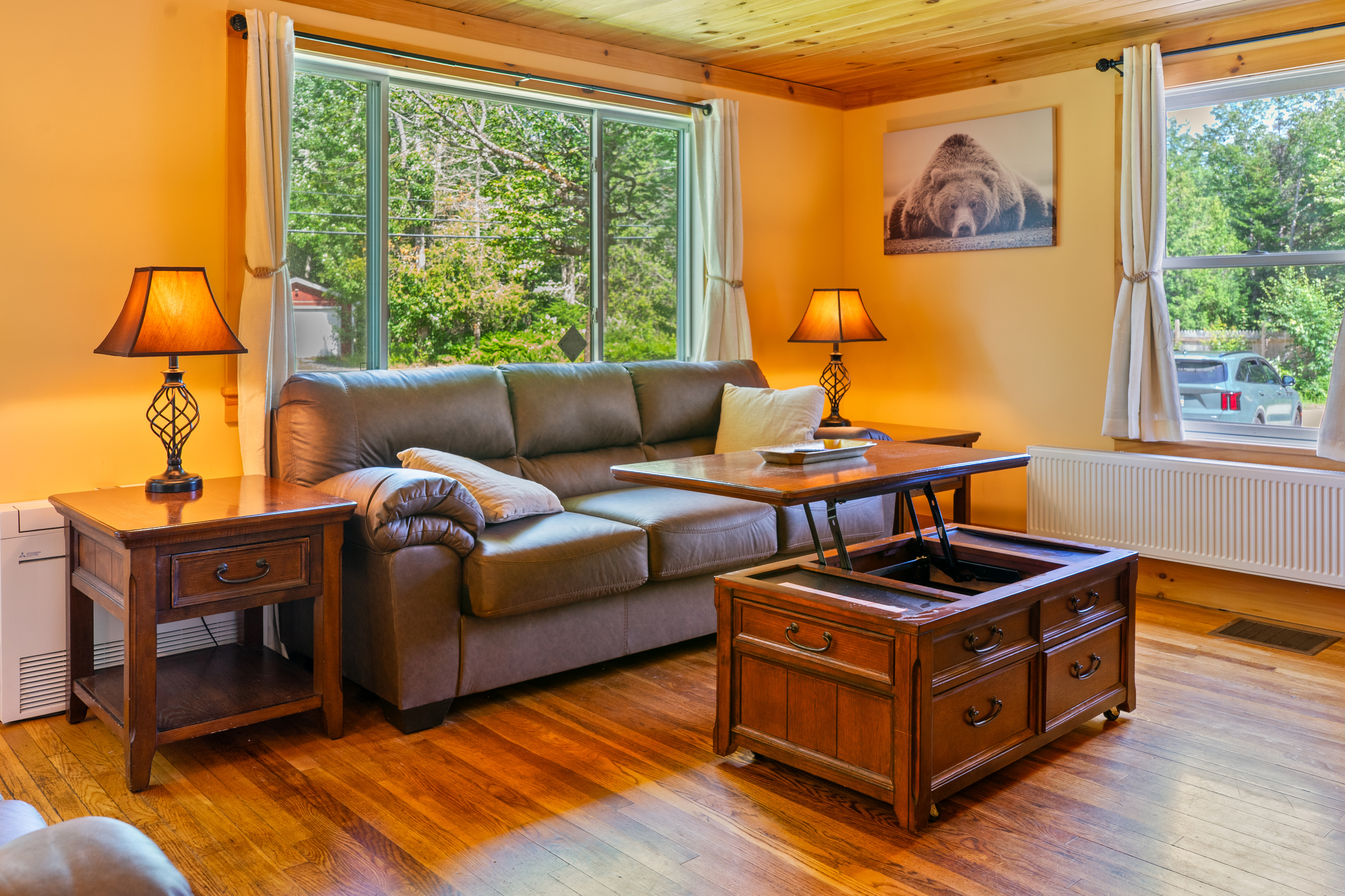 Unwind in the inviting living room featuring comfortable sofa seating, rich hardwood floors, and warm ambient lighting. A multi-functional lift-top coffee table easily adjusts for working, gaming, or casual dining right from the couch.