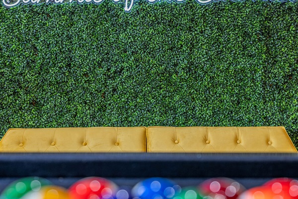 Neon sign, hedge wall, and stylish yellow sofa make for the perfect photo-op.