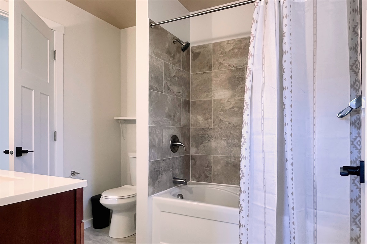 Clean and bright full bath with tub/shower combo — stocked with essentials and fresh towels.