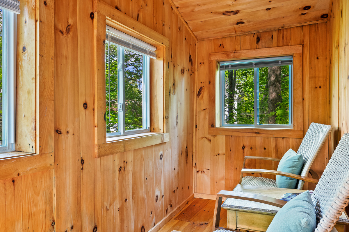 Another view of the Pine Breeze Room, looking from the cabin doorway. Wrap-around screened windows flood the natural wood space with light and fresh island air. A tranquil, pet-friendly spot to relax and watch the surrounding Acadia forest.