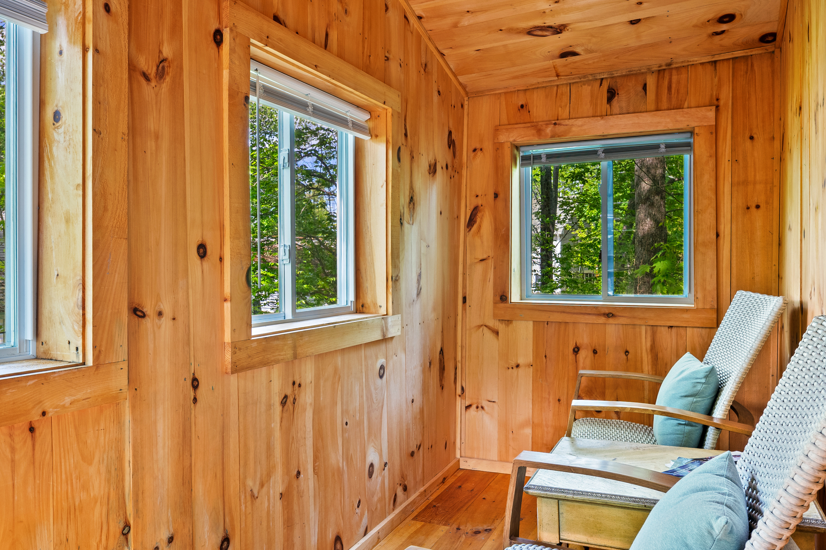 Another view of the Pine Breeze Room, looking from the cabin doorway. Wrap-around screened windows flood the natural wood space with light and fresh island air. A tranquil, pet-friendly spot to relax and watch the surrounding Acadia forest.