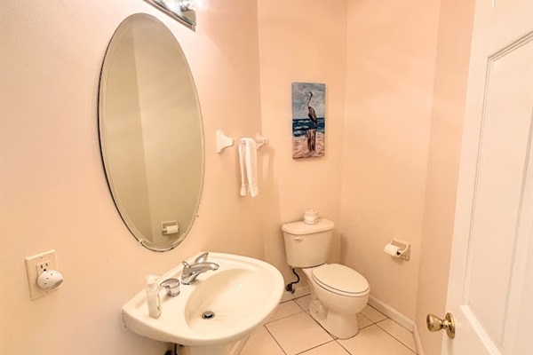 Convenient half bathroom with pedestal sink, tile flooring, and clean neutral finishes.