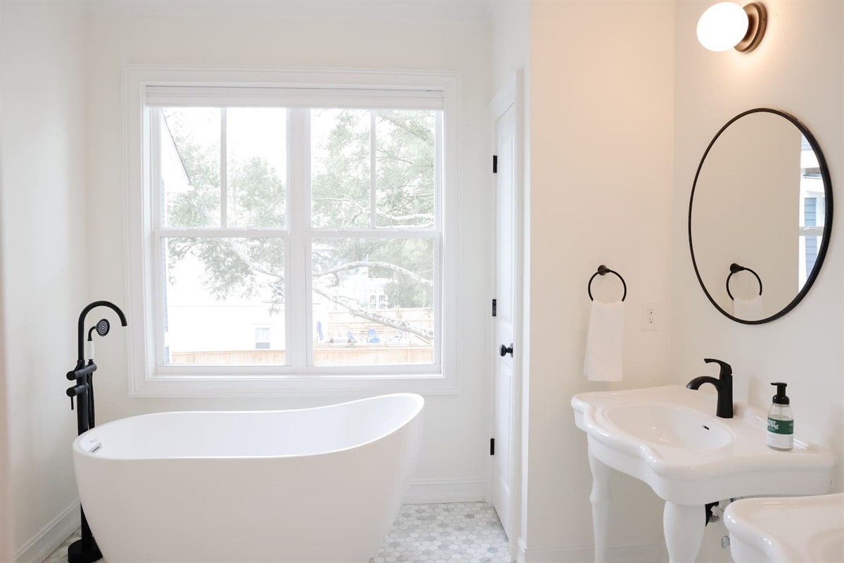 The soaking tub is the star of the show in the primary bathroom. Enjoy a relaxing bath with views of the beautiful live oaks.