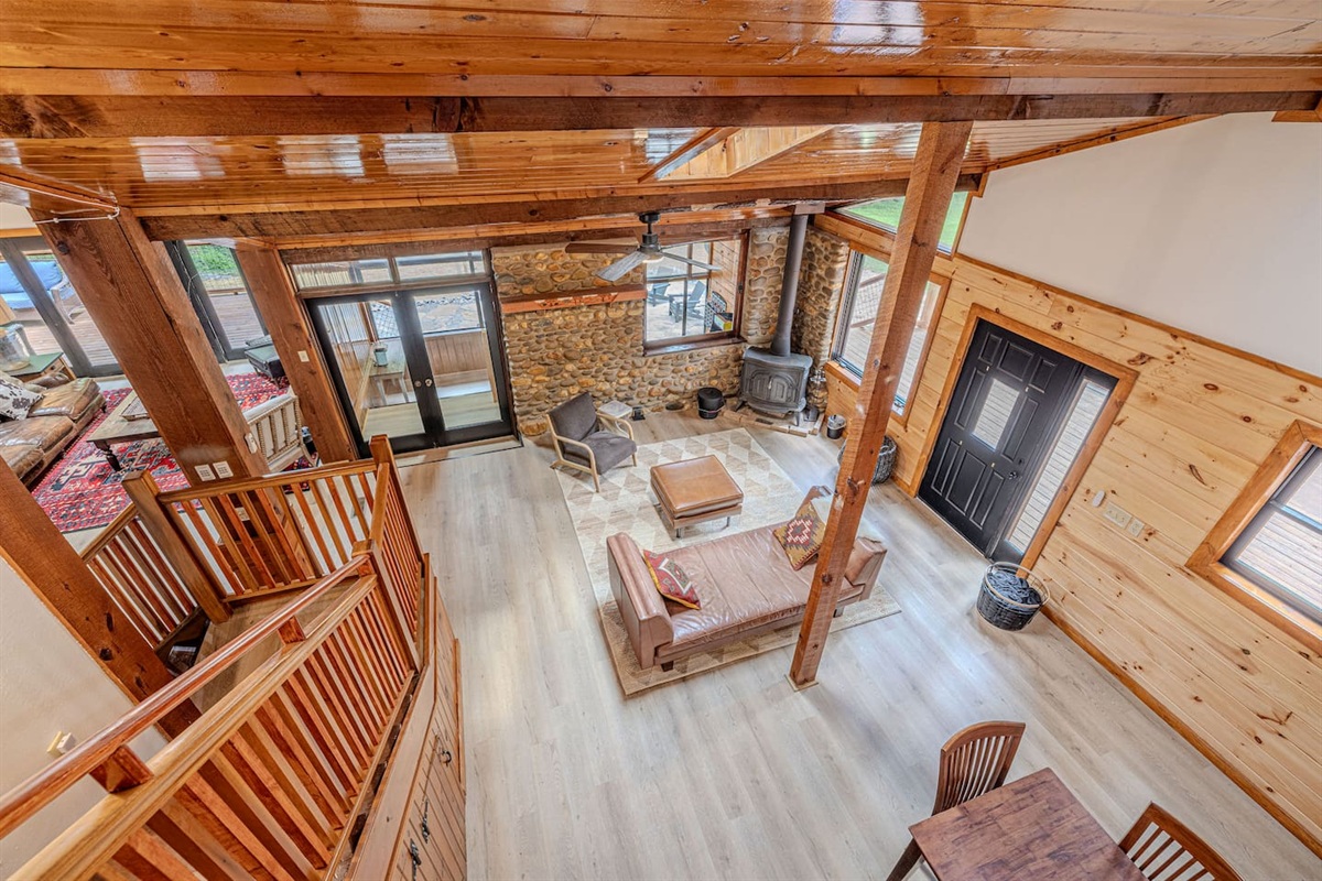 An overhead view reveals the dramatic scale of this stunning living space, where soaring cathedral ceilings, rich stonework, and layered seating create an inviting retreat for gathering.