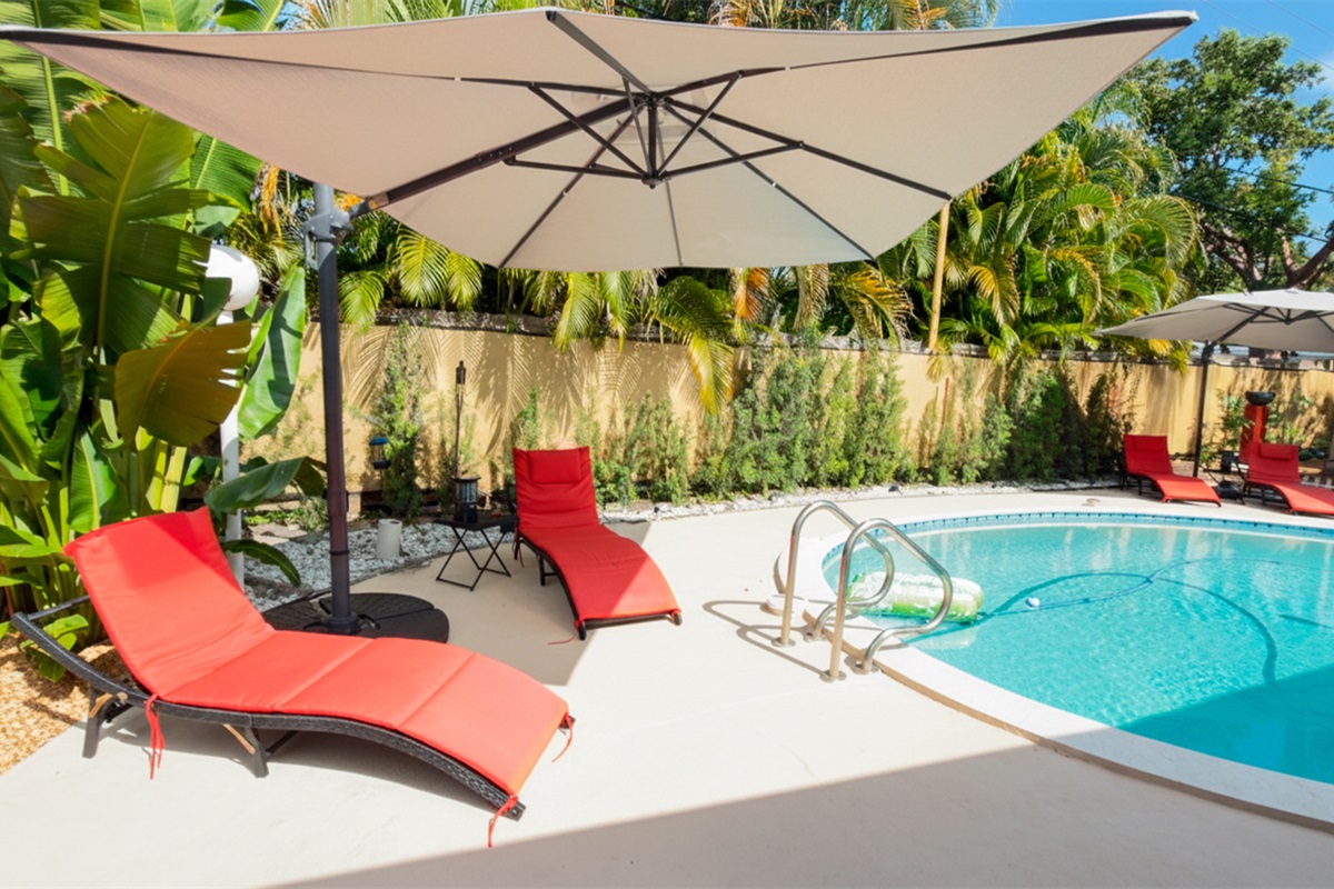 Daytime pool area with shaded loungers and tropical surroundings at Garden of Manors.