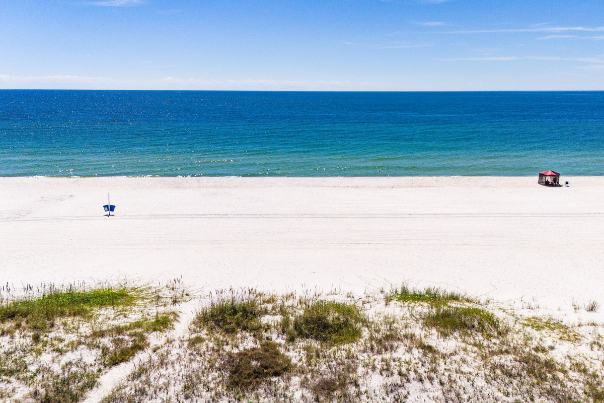 Scenic beach aerial showing turquoise Gulf waters, white sand, and the peaceful coastal landscape surrounding the vacation rental community.