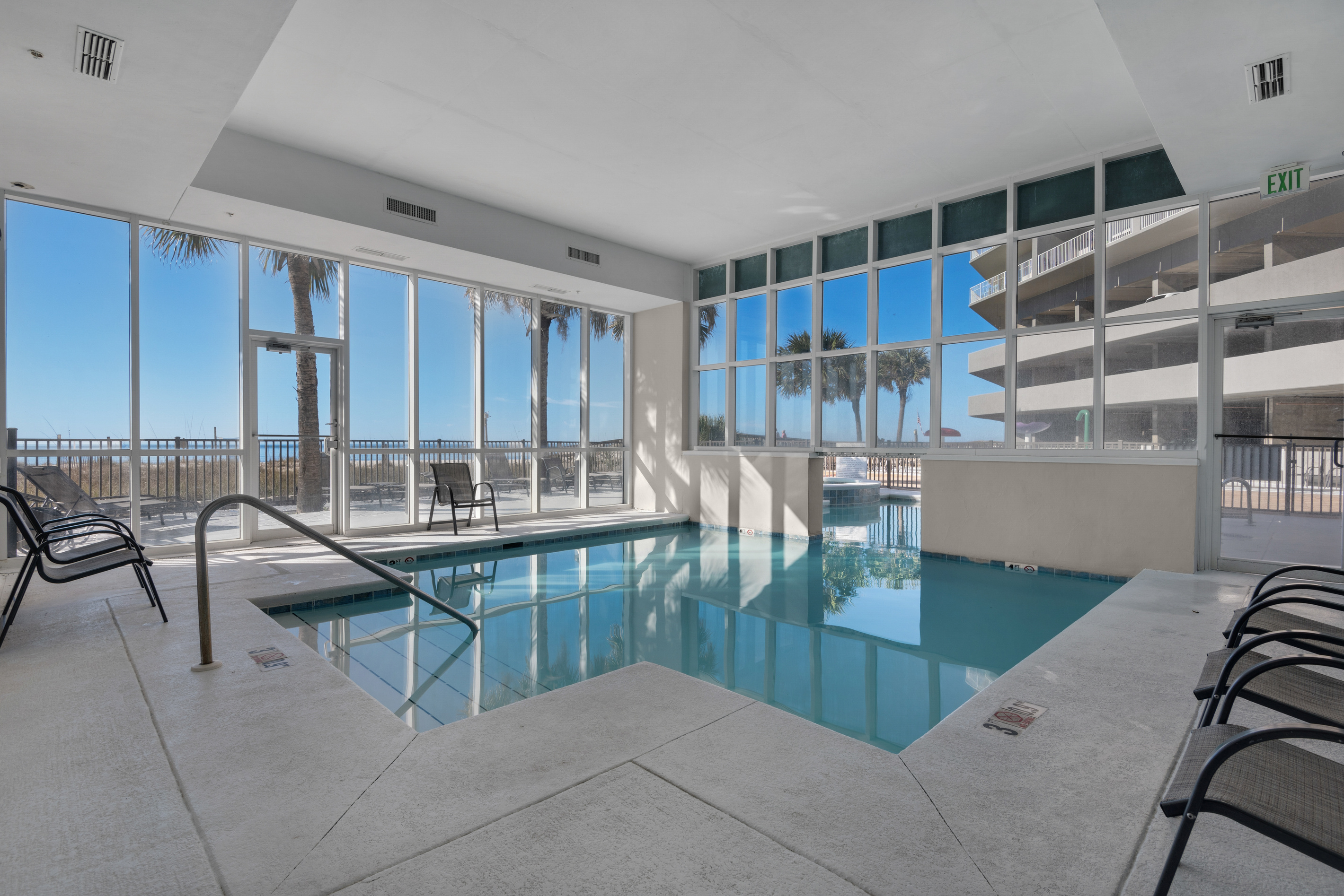 Indoor pool with Gulf views through the surrounding windows.