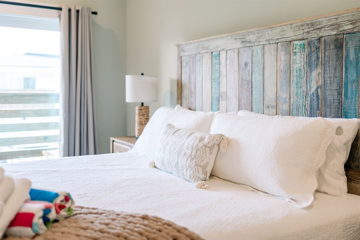 Comfortable king bedroom featuring soft coastal tones and natural light.