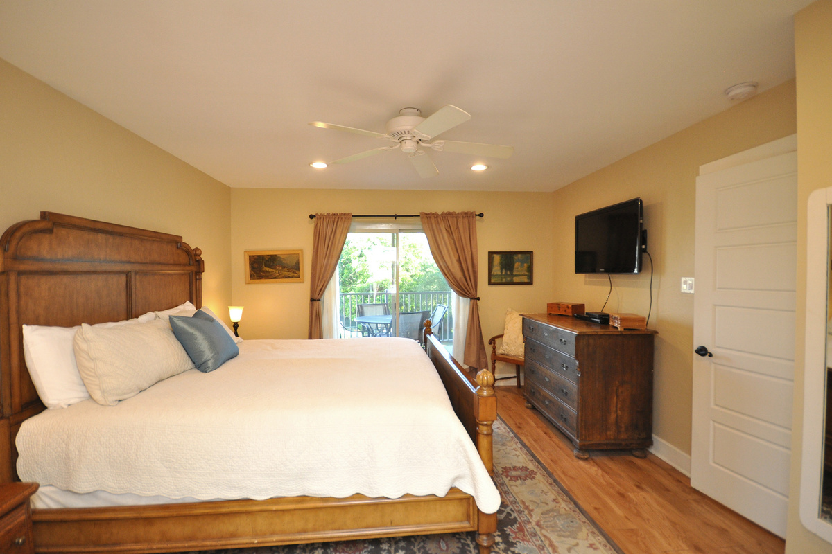 Primary Bedroom with access to balcony and flat screen TV.