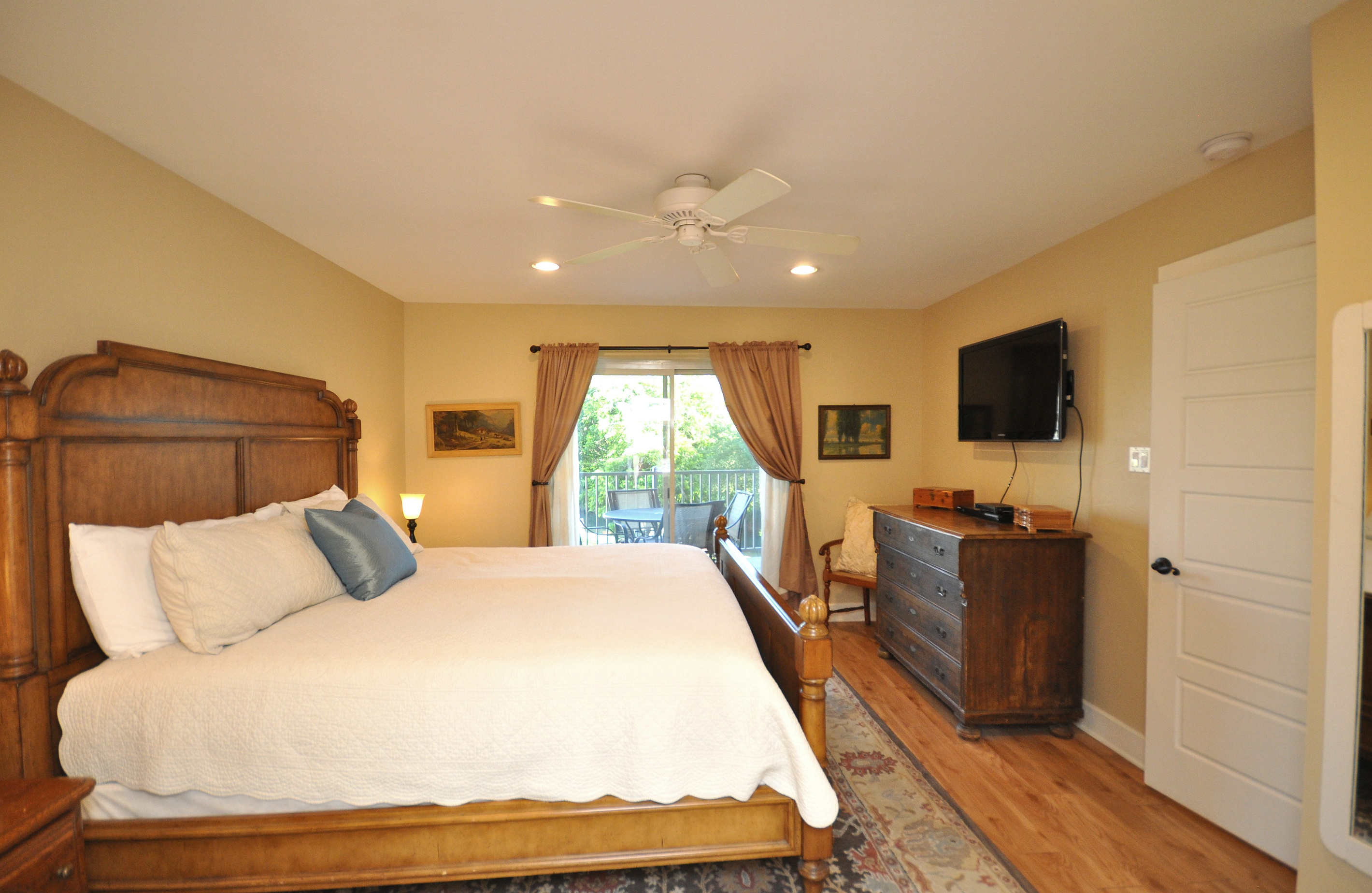 Primary Bedroom with access to balcony and flat screen TV.