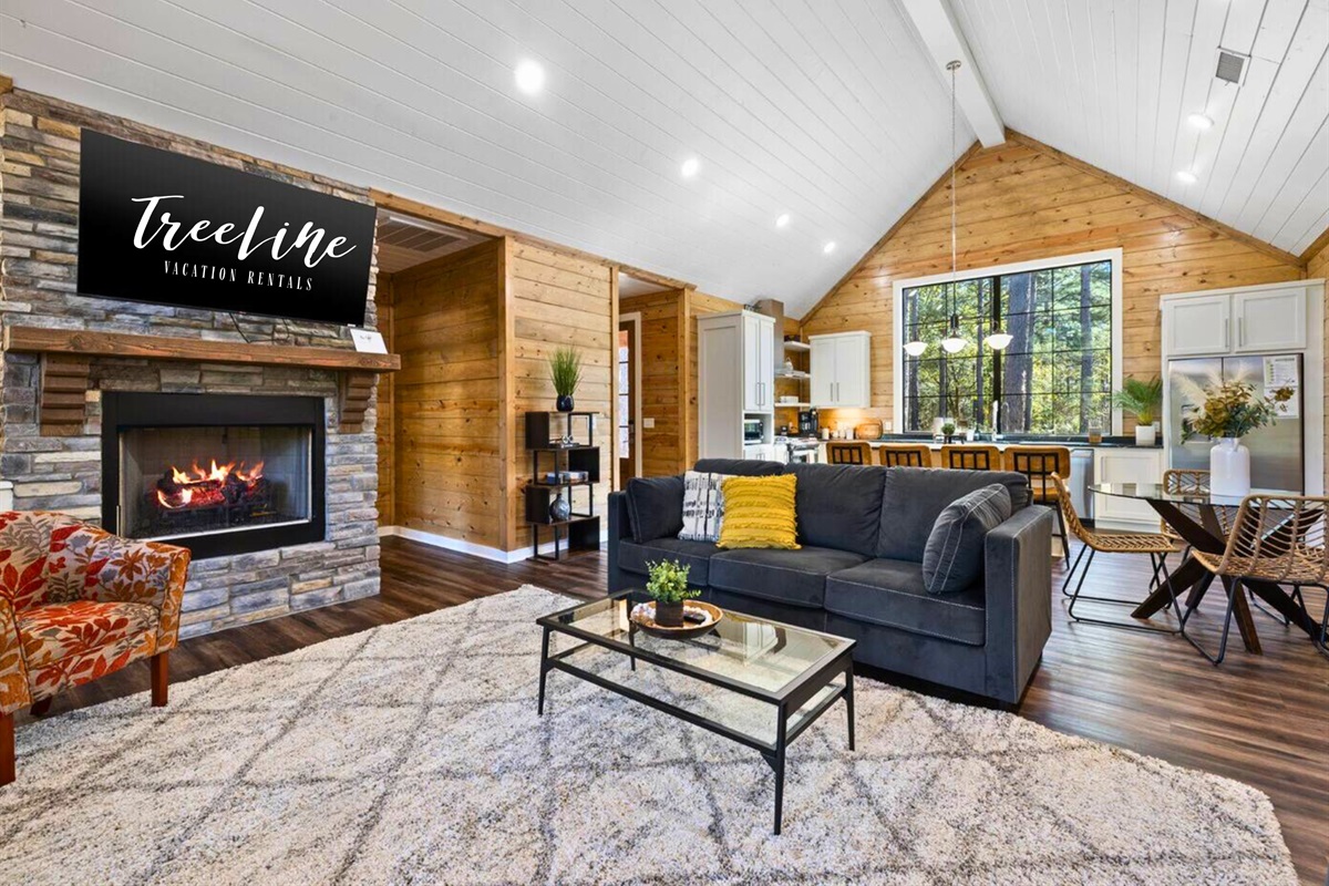 Sink into comfort by the fireplace, your living room framed by nature.