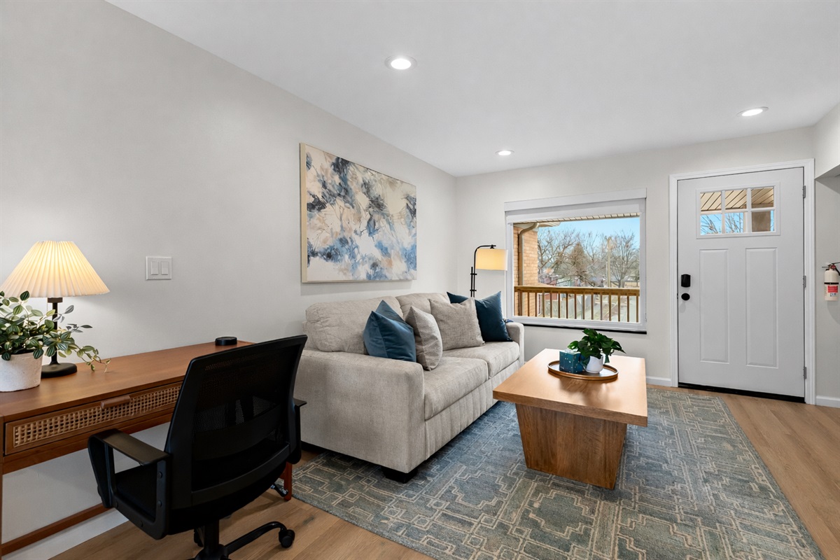 Bright, open living area with cozy seating, a dedicated workspace, and natural light—ideal for relaxing, working, or enjoying a quiet stay.