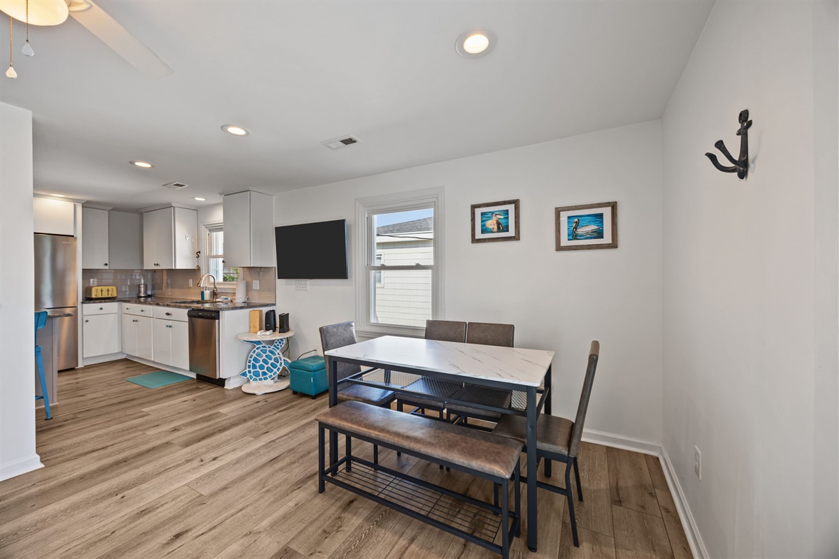 Dining table with bench seating and a clear sightline into the fully equipped kitchen