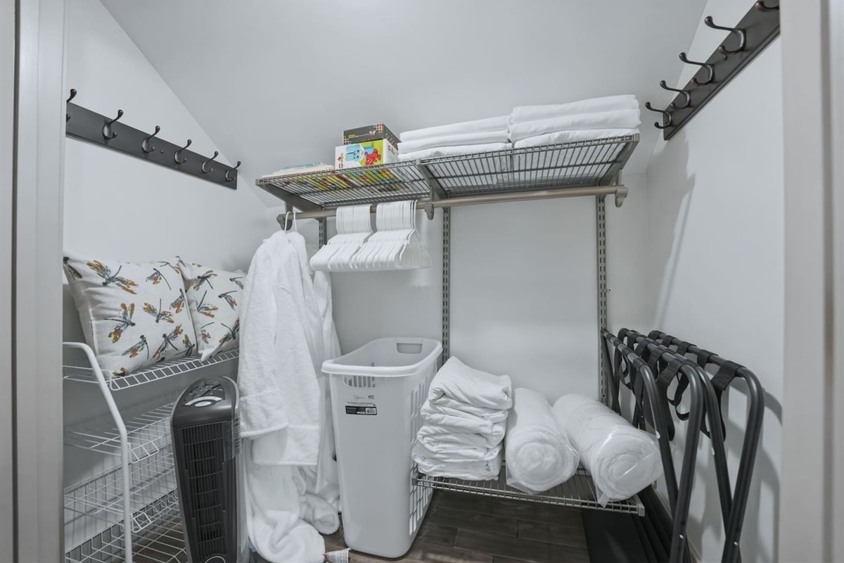 Walk-in closet with ample storage, hangers, fresh linens, pillows, and laundry essentials for a comfortable extended stay.