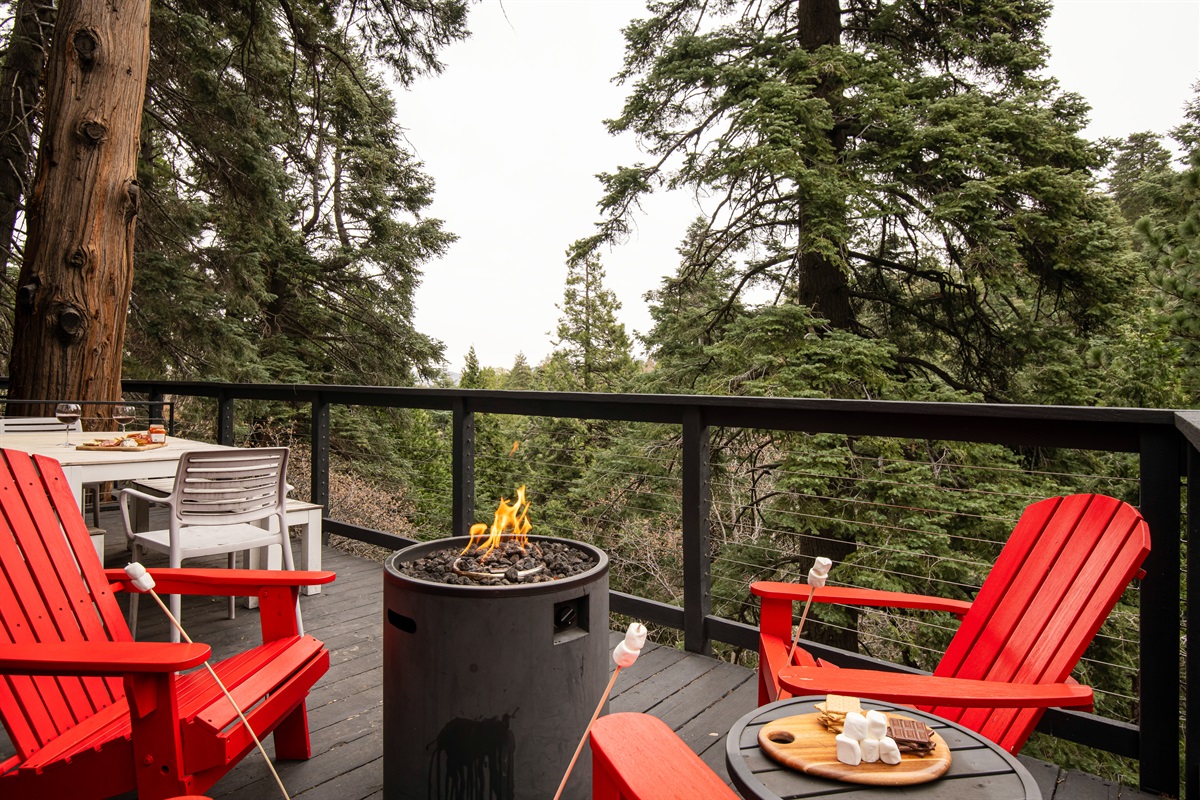 Outdoor fire pit with Adirondack seating and forest views—perfect for cozy nights, s’mores, and relaxing during your Lake Arrowhead cabin stay.